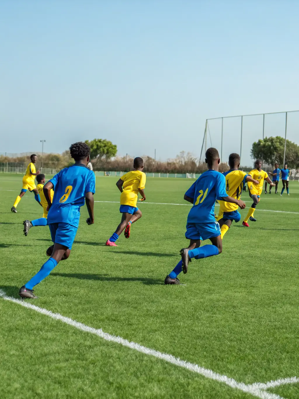A group of students playing soccer on a green field during a sunny day, representing the soccer program offered by ASSOCIATION SPORTIVE DU COLLEGE PUBLIC DE HILLION.